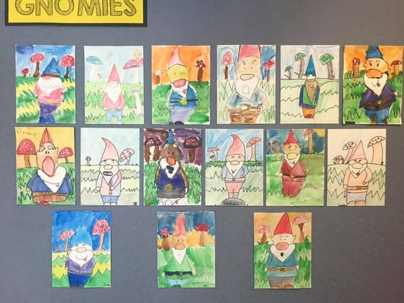 Photo of student art posted in grid pattern on wall.  All student art features paintings of gnomes.