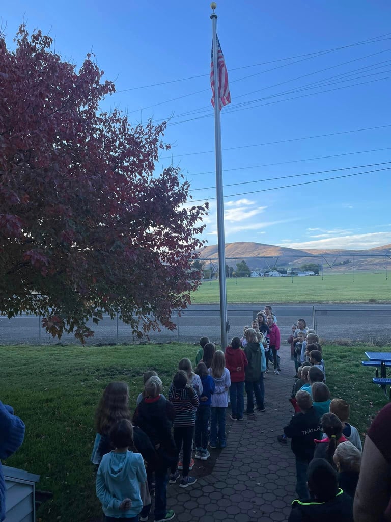 Photo of Damman Students lined up facing school flag pole. 