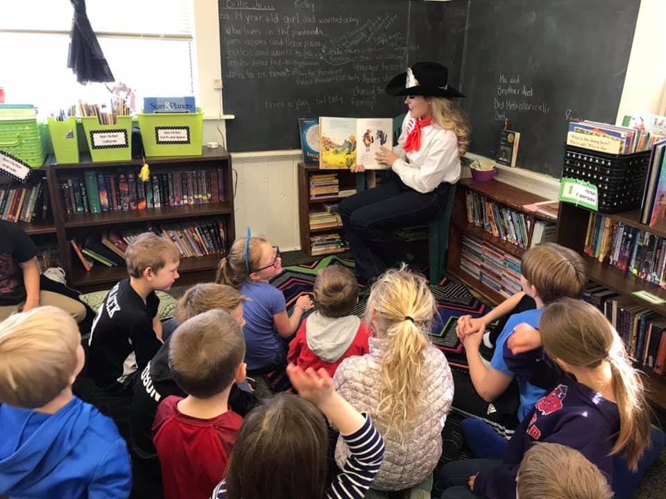 Photo of a Rodeo princess reading a picture book to students at Damman.